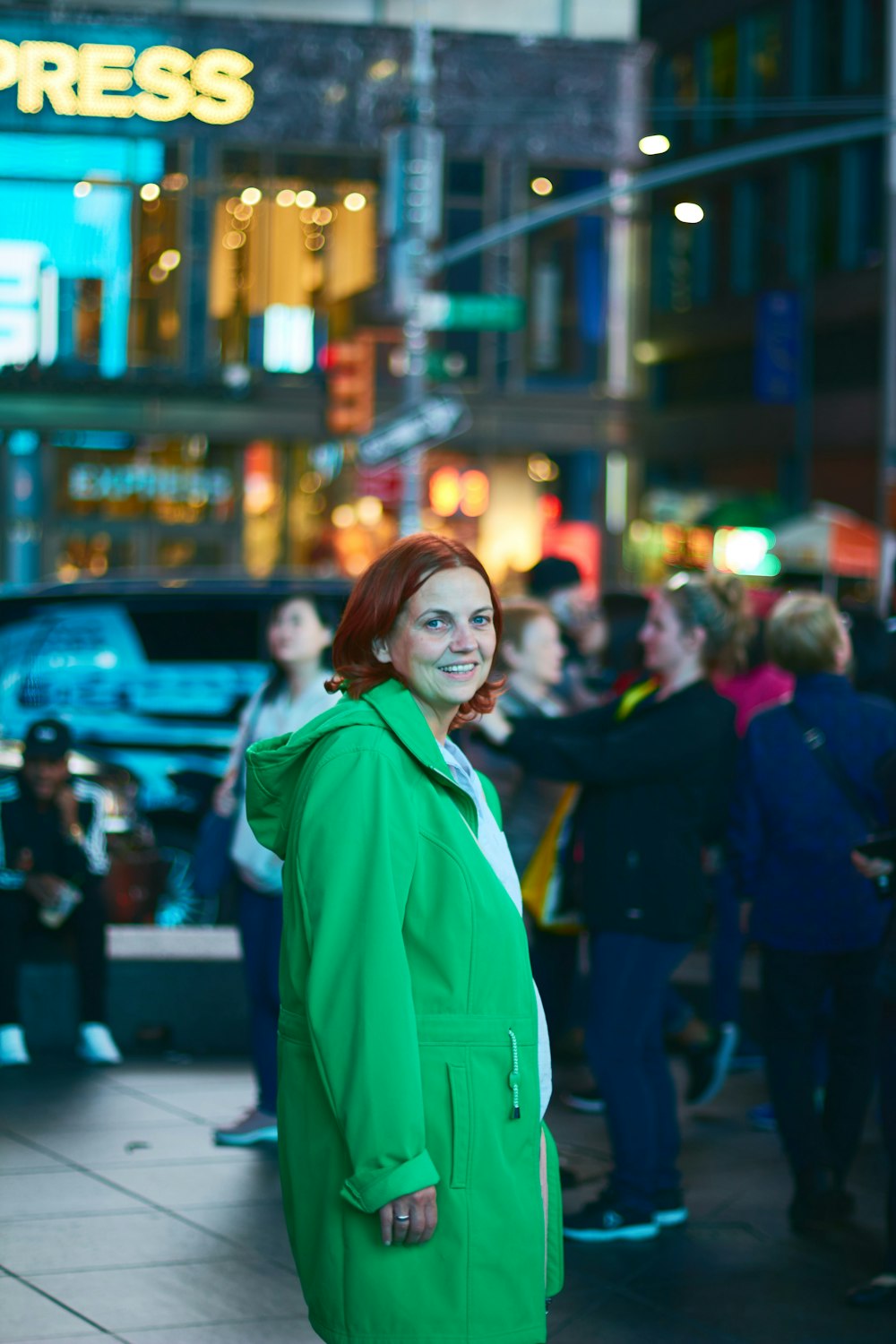 woman in green hoodie standing on street during night time