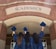 three girls in graduation gowns hold their caps in the air