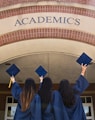 three girls in graduation gowns hold their caps in the air