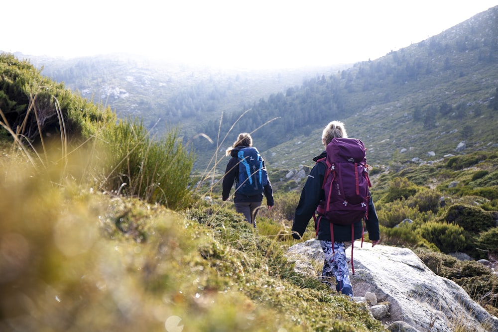 2 women walking on rocky mountain during daytime