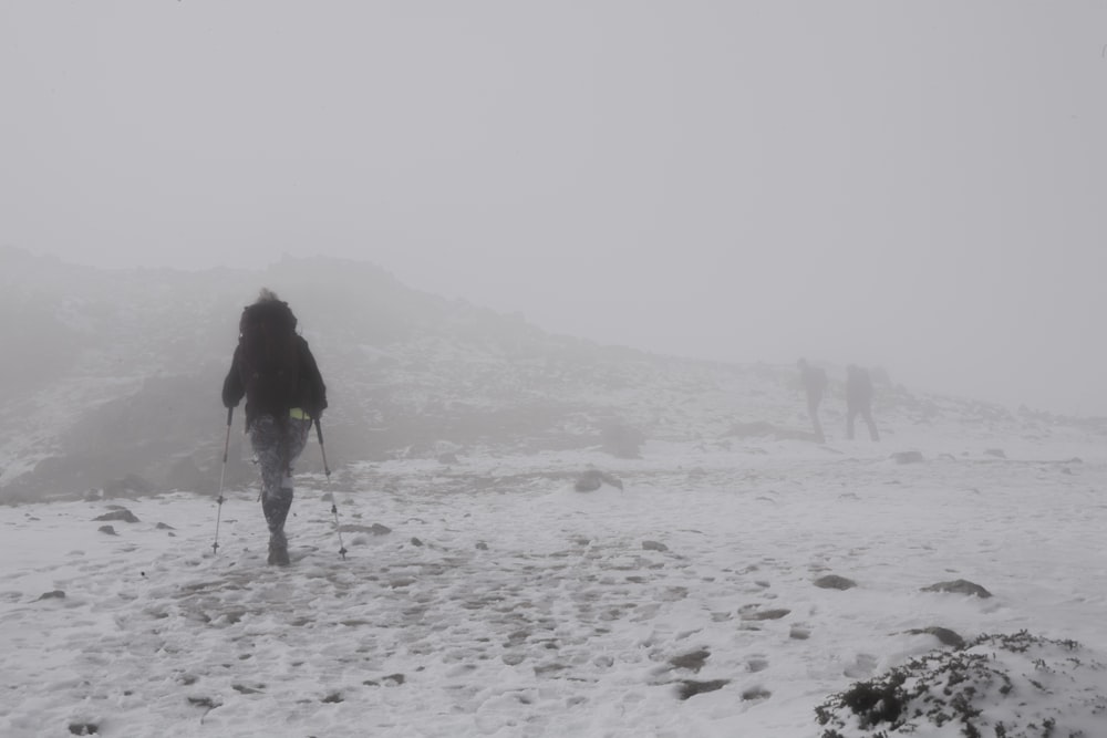 woman in black jacket walking on snow covered field during daytime