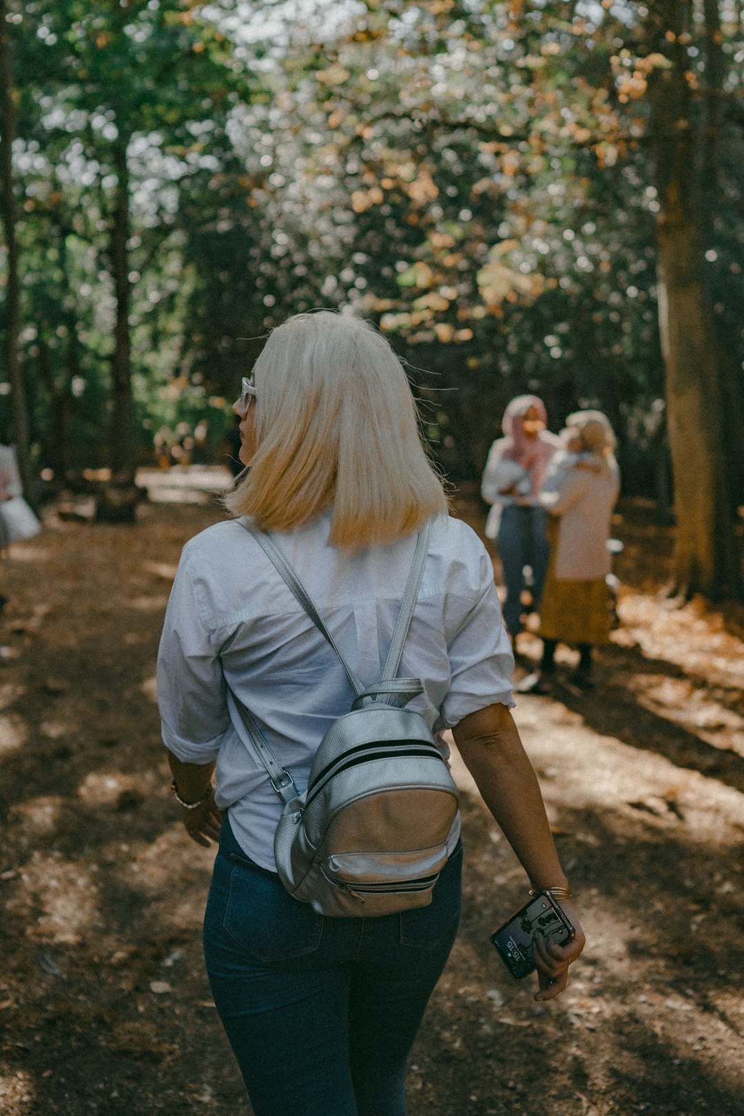 woman in gray shirt and blue denim jeans standing on brown soil during daytime