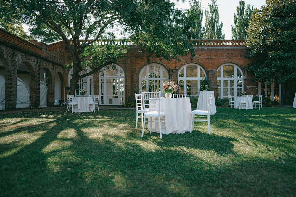 white table and chairs on green grass field near brown concrete building during daytime