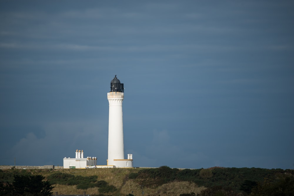 white lighthouse on green grass field under blue sky during daytime