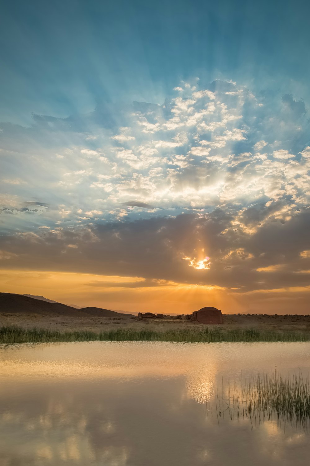 Plan d’eau près d’un champ d’herbe verte au coucher du soleil