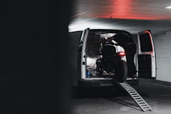 Close-up of a sleek road bike being loaded gently into a van by a professional courier.