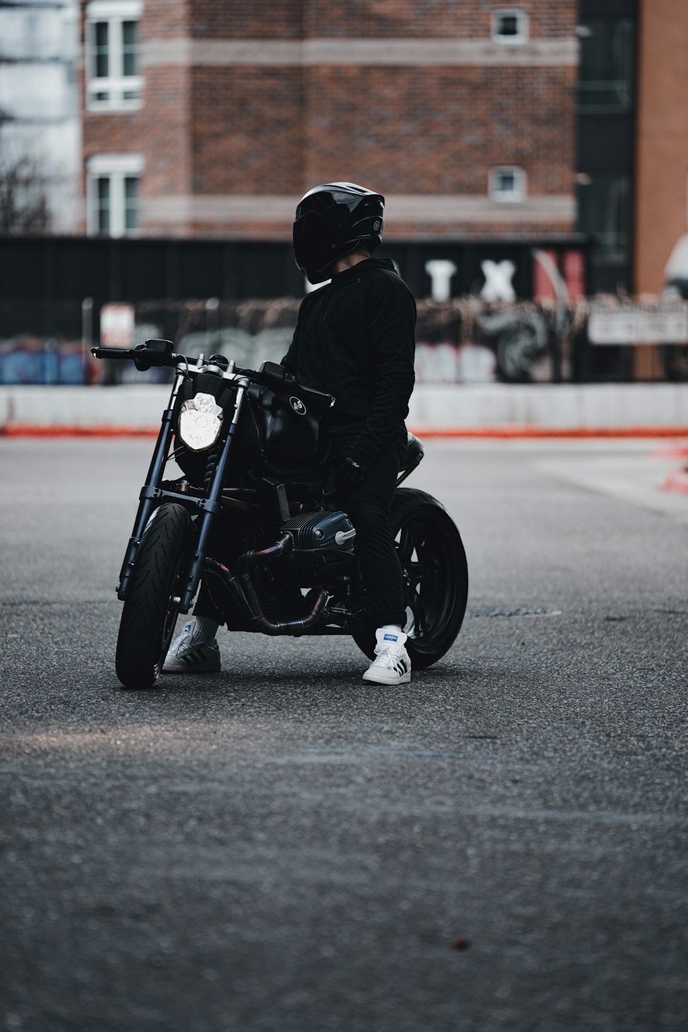 man in black jacket and black pants sitting on black motorcycle on road during daytime