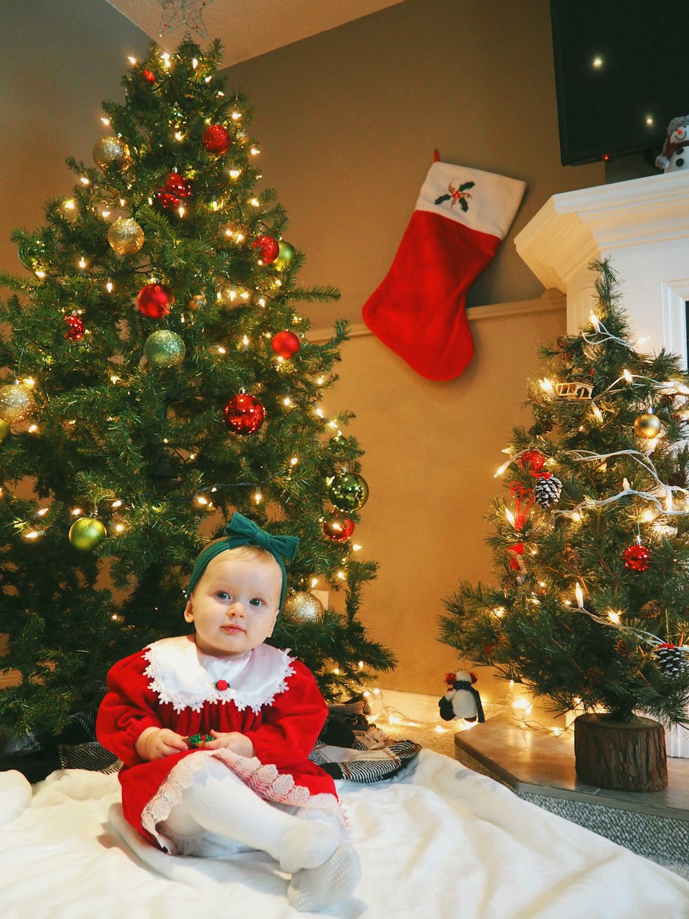 girl in red and white santa costume standing beside green christmas tree