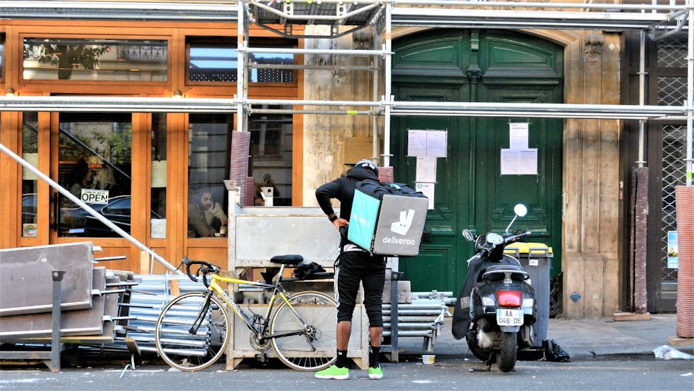 man in black jacket and black pants holding green and white book