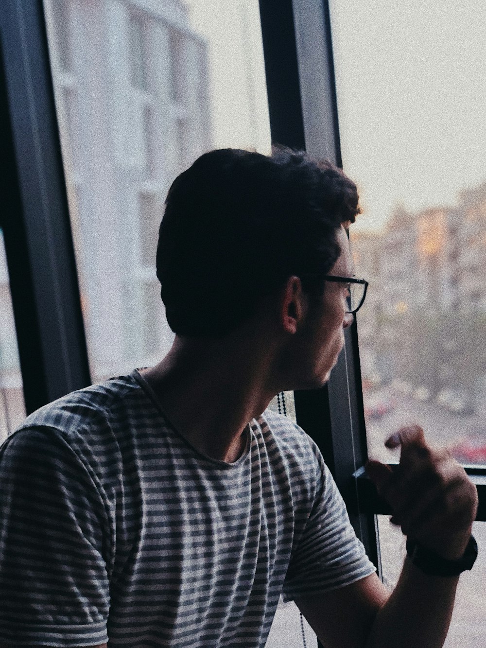 man in white and black striped crew neck shirt holding black smartphone