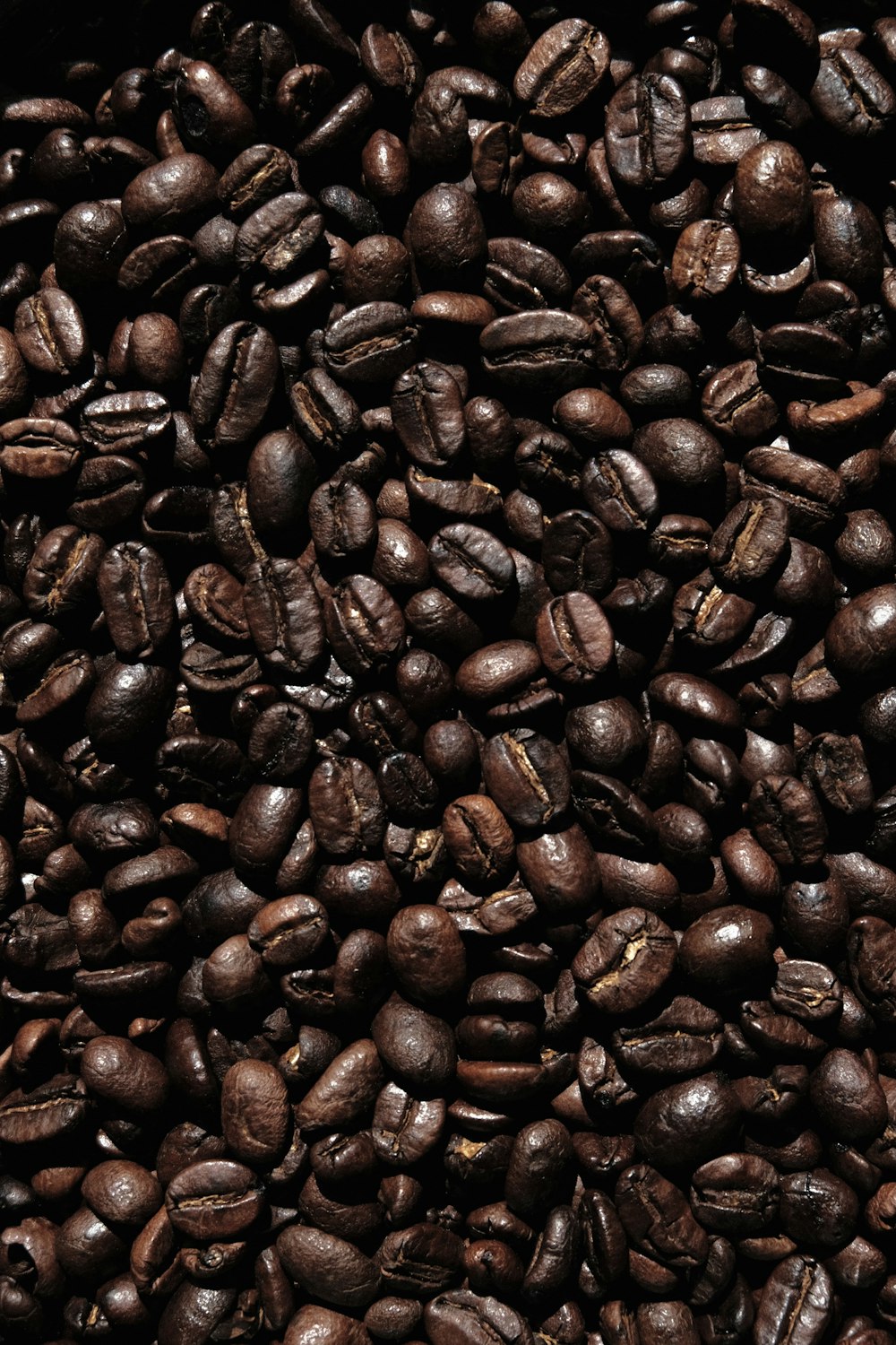 brown coffee beans on black surface