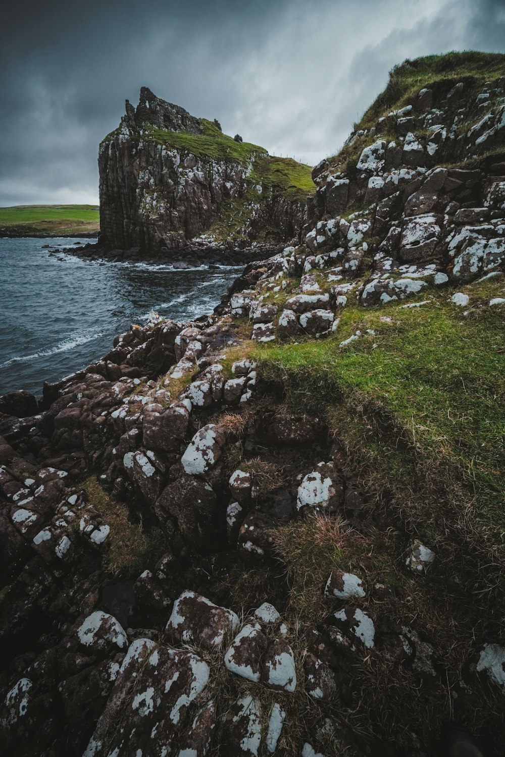 green and gray rock formation beside body of water during daytime