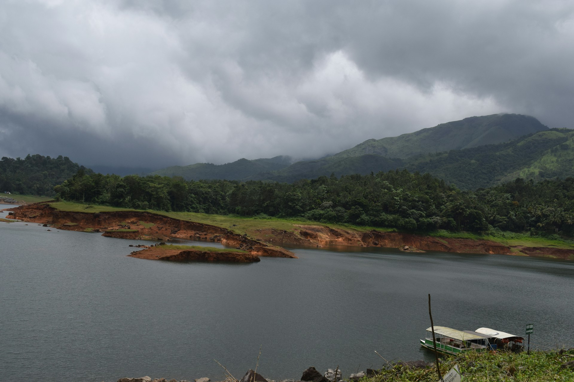 green and brown mountains beside lake under white clouds during daytime
