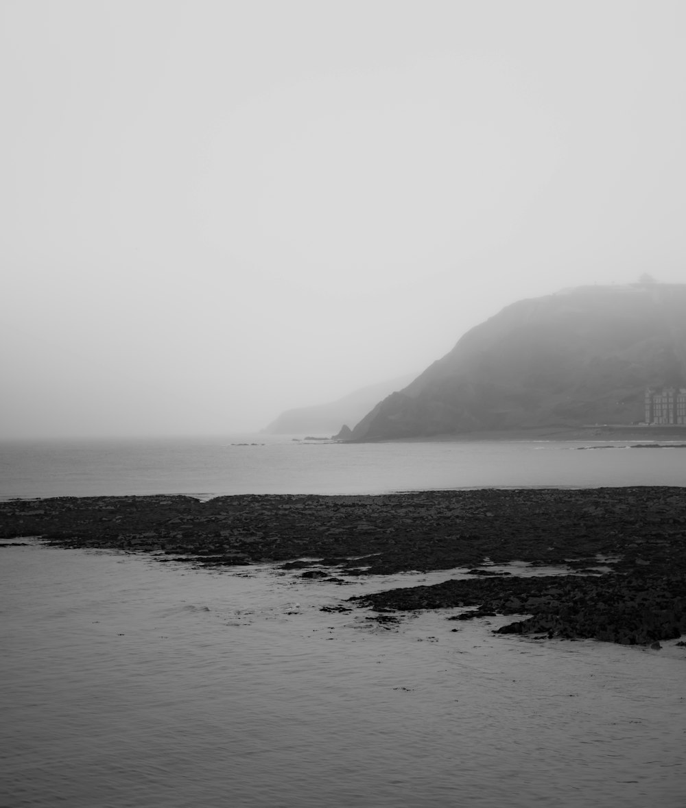 grayscale photo of body of water near mountain