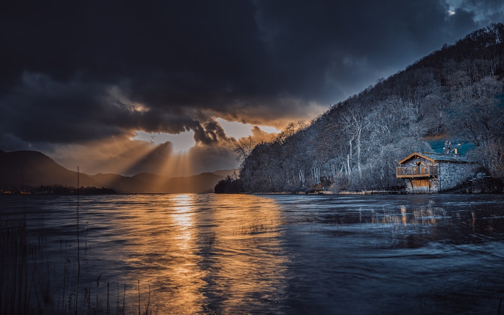 brown wooden house on body of water near mountain during night time