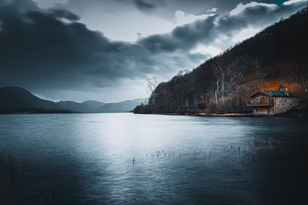 body of water near trees under cloudy sky during daytime