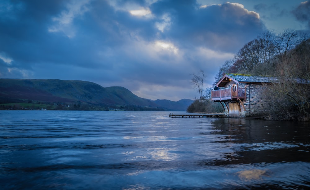 red and white house on body of water near green trees under blue sky during daytime