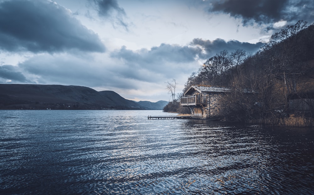 white and brown house near body of water under cloudy sky during daytime