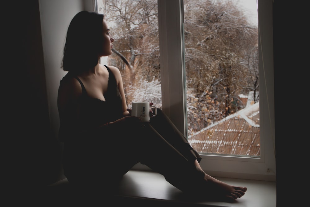 woman in black tank top sitting on window