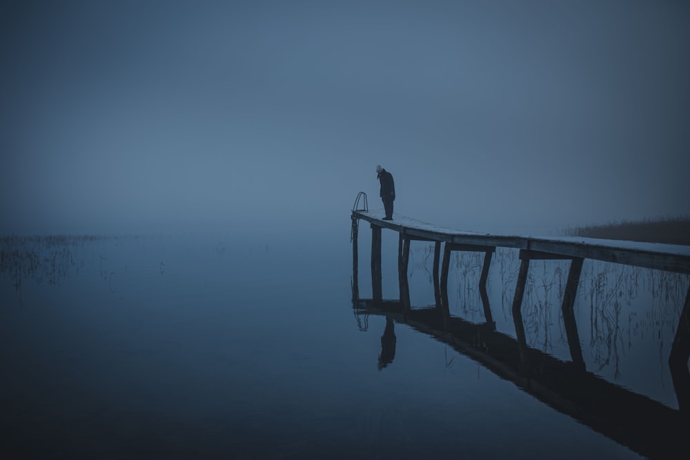 2 person standing on wooden dock in grayscale photography