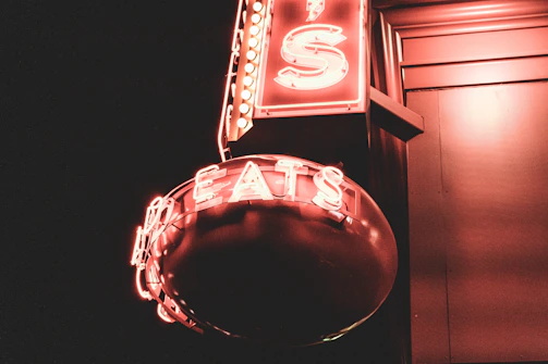 A cinematic shot of the Beats vs Eats logo illuminated with smoky red and orange lighting.