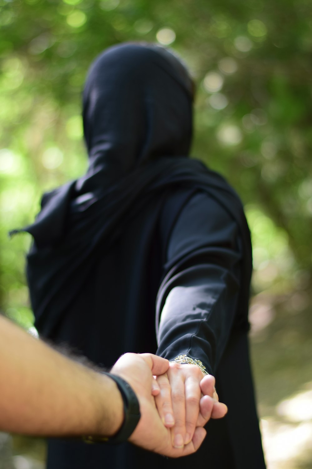 person in black hijab holding hands