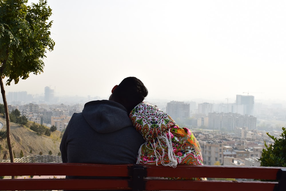 man and woman sitting on red wooden bench during daytime