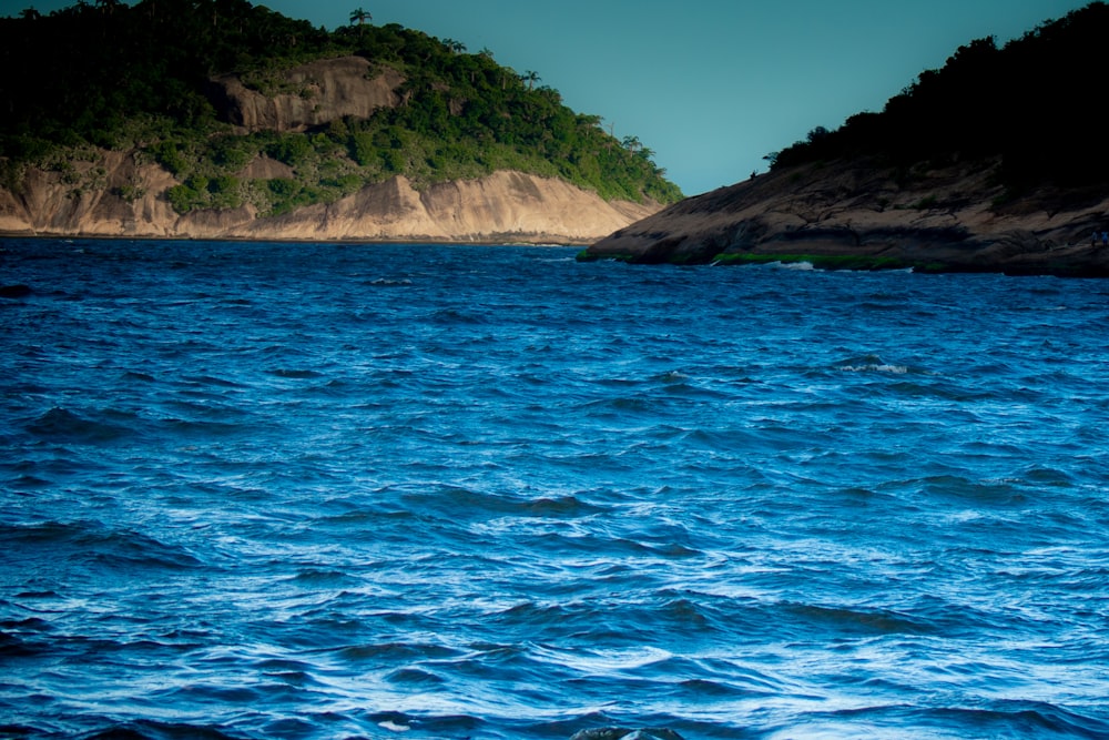 brown rocky mountain beside blue sea during daytime