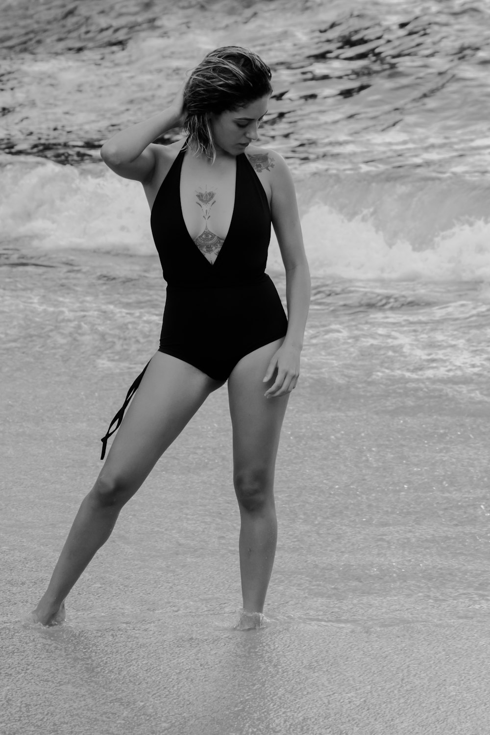 woman in black one piece swimsuit standing on beach shore