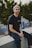 man in black crew neck t-shirt and blue denim jeans sitting on gray concrete bench