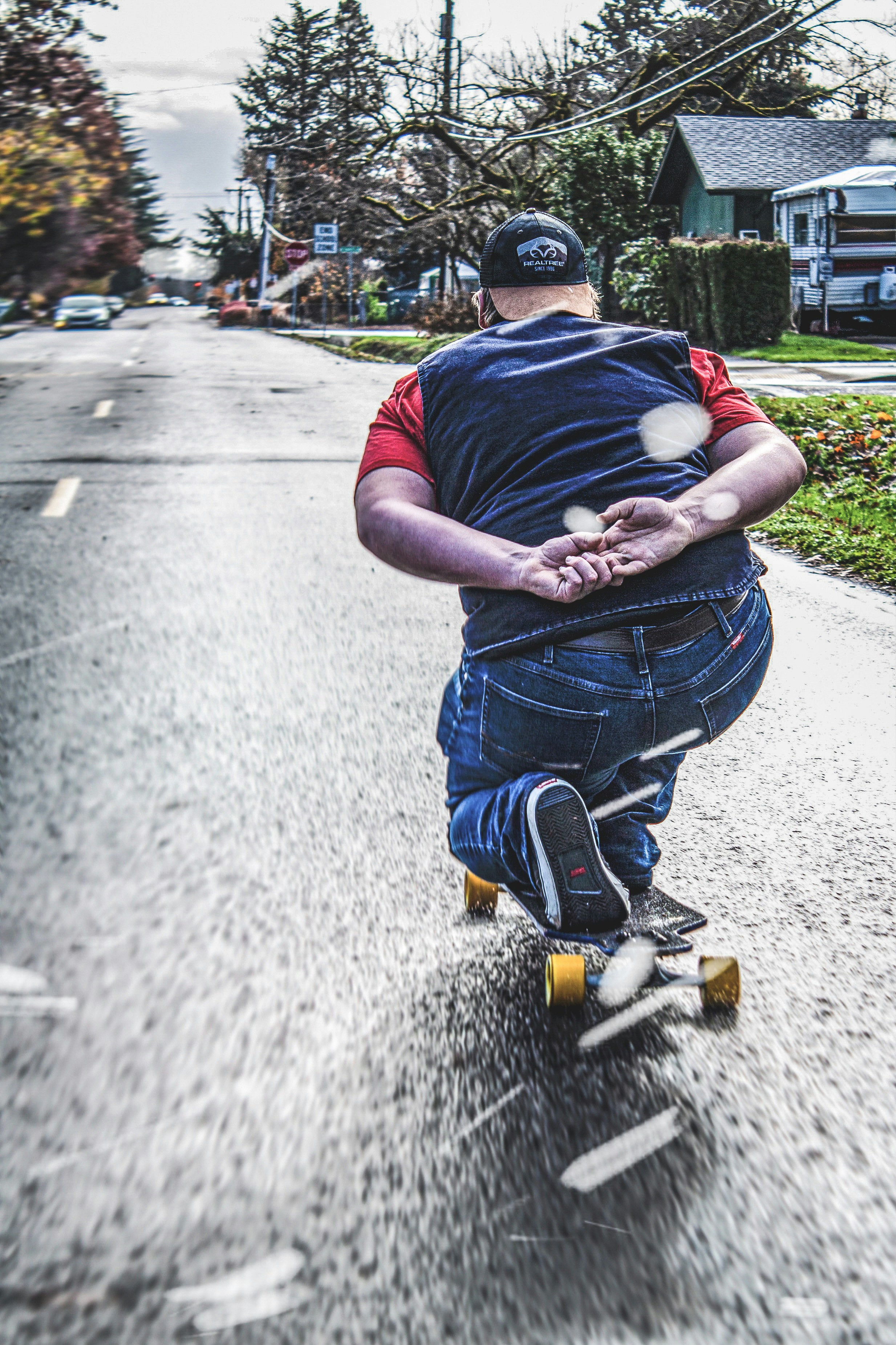 Hombre con pantalones cortos de mezclilla azul y camiseta azul sentado en un camino de concreto gris durante el día