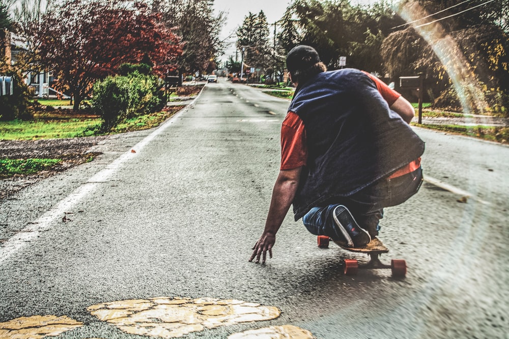 man in blue t-shirt and black pants sitting on concrete pathway during daytime