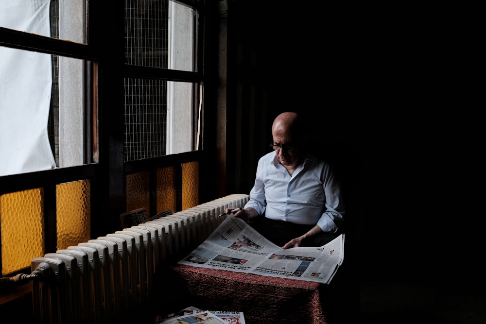 man in white dress shirt reading newspaper