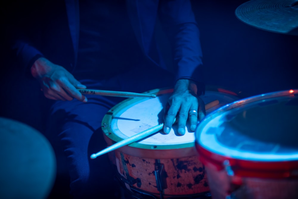 person in blue long sleeve shirt holding drum sticks