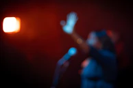 Artistic thumbnail-style image featuring a political discussion setup with microphones and warm backlighting.