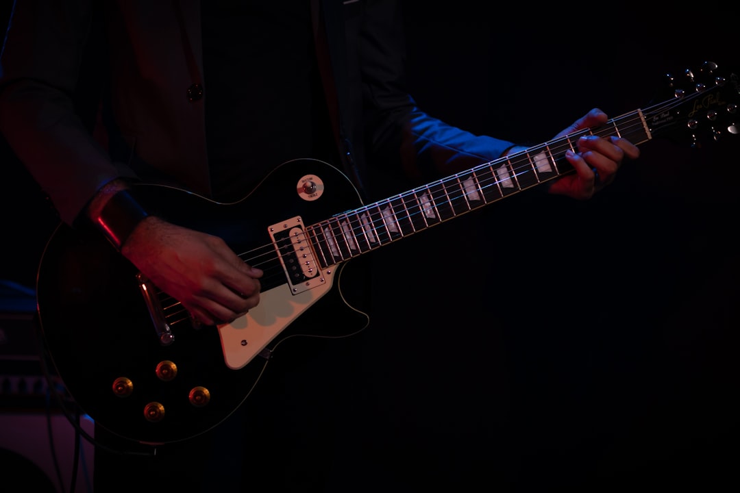 man in black suit playing white electric guitar