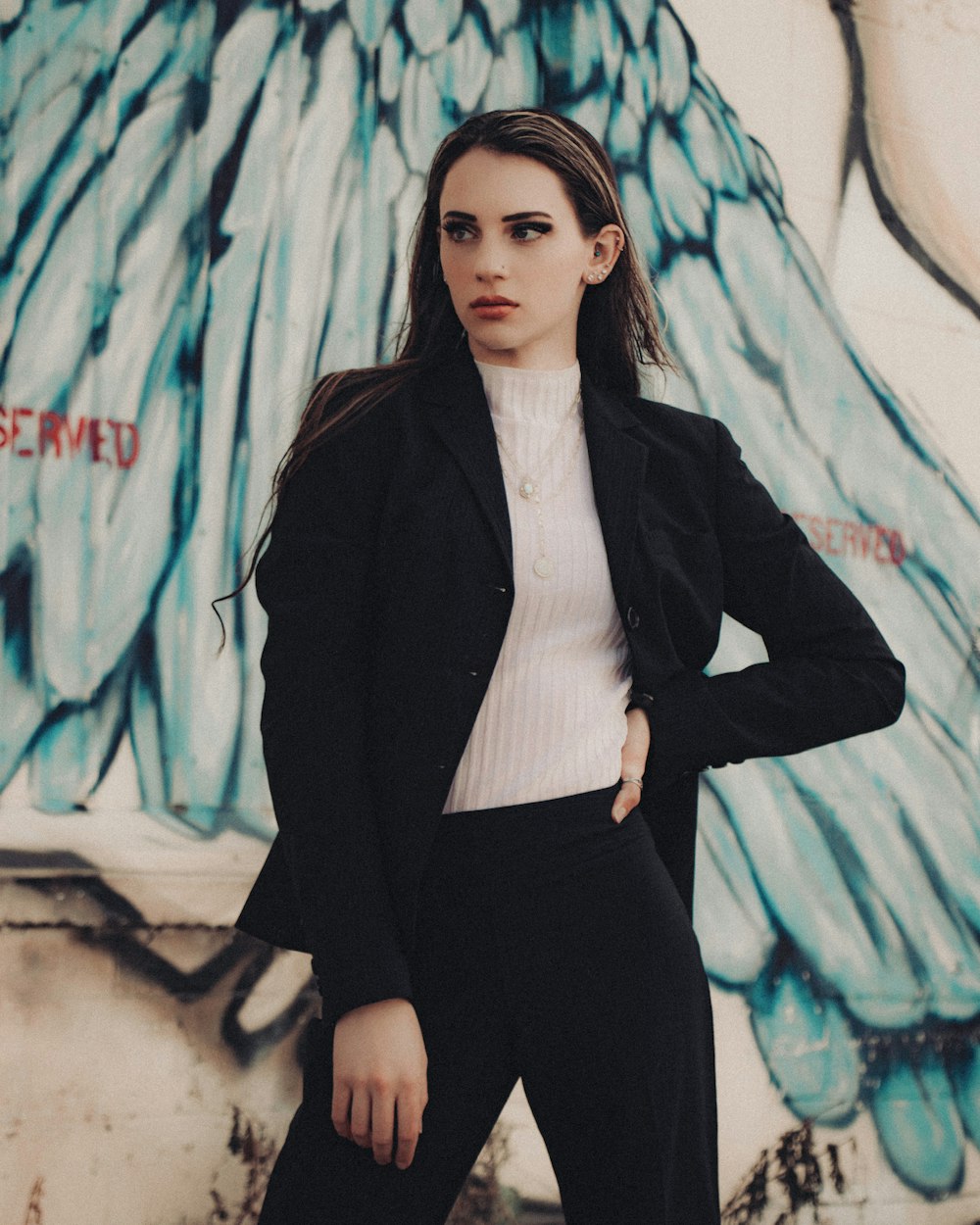 woman in black blazer standing beside graffiti wall