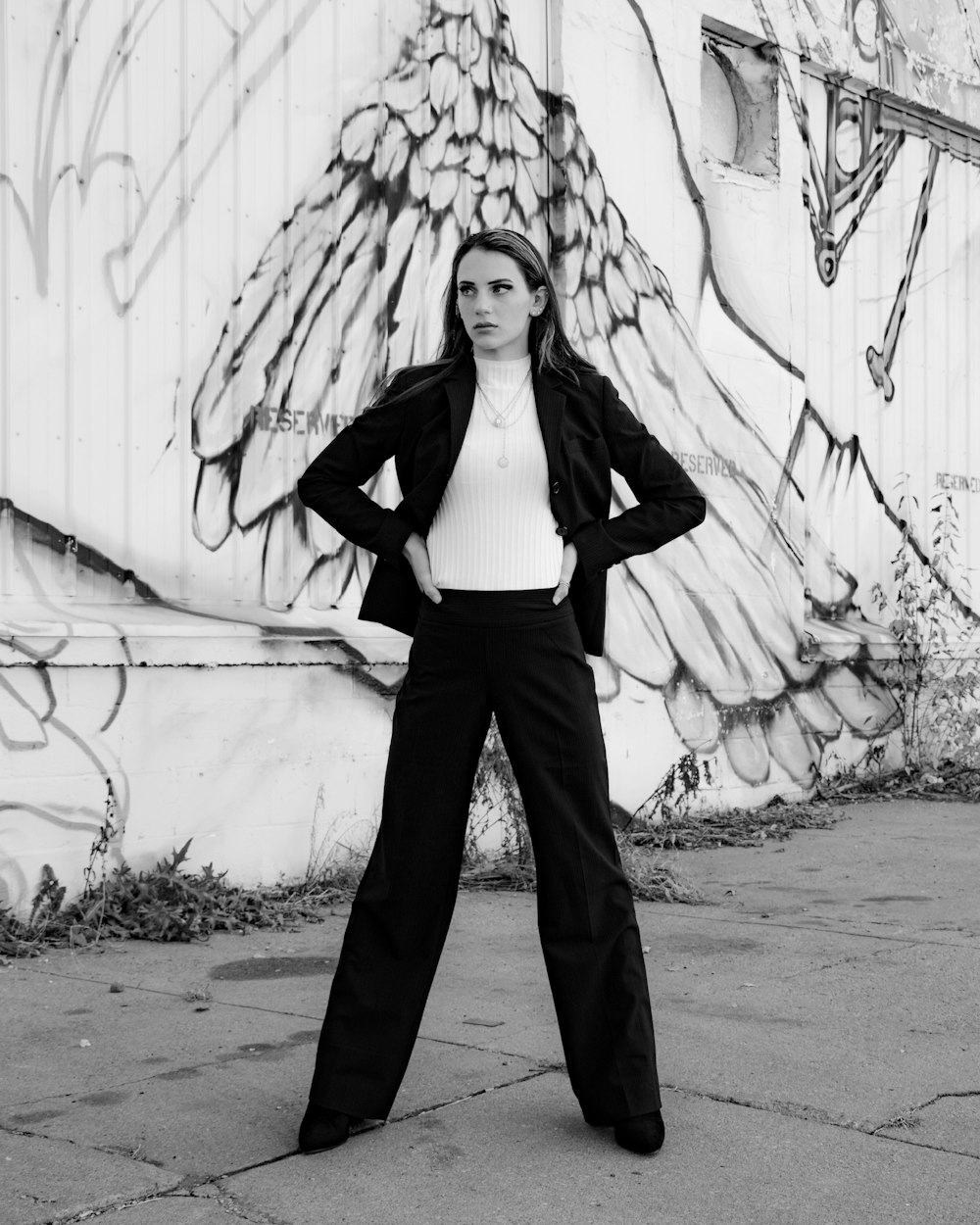 woman in black vest and black pants standing beside wall