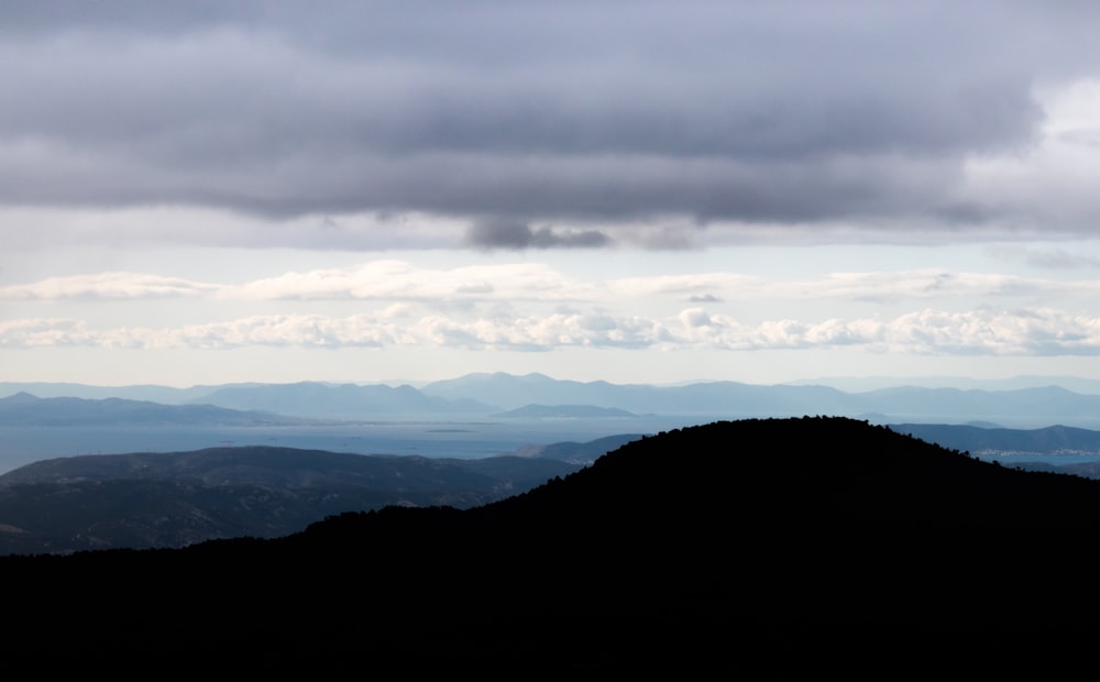 silhouette of mountains under cloudy sky during daytime