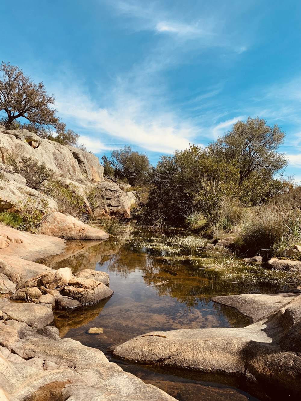 brown rocky mountain beside river under blue sky during daytime