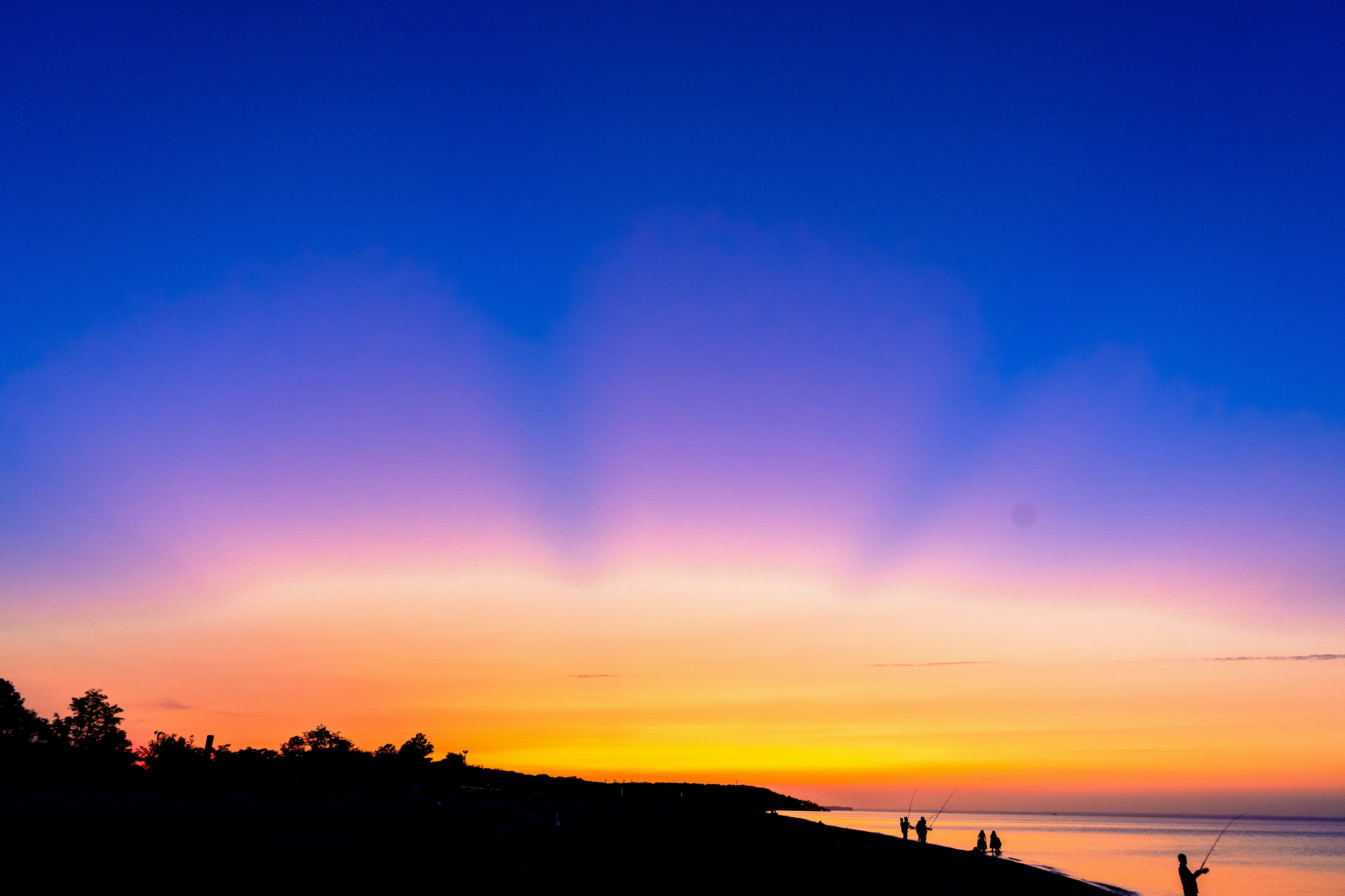 Plage de Dakar au coucher du soleil, ciel orange et rouge, pêcheurs sur des pirogues colorées