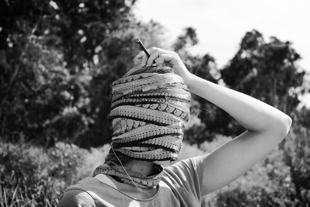 grayscale photo of person wearing knit cap and holding pen