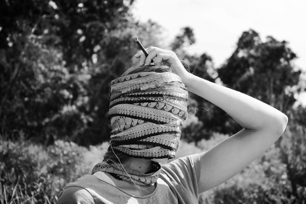 Foto in scala di grigi di una persona che indossa un berretto a maglia e tiene la penna