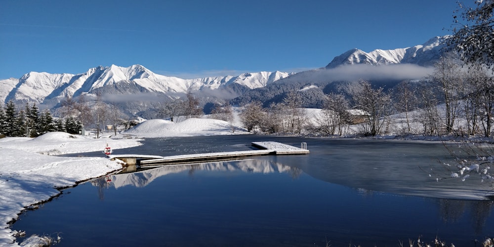 snow covered mountain near lake under blue sky during daytime