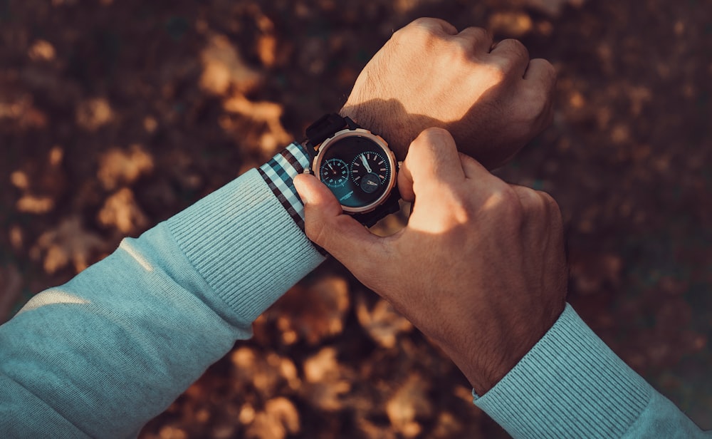 person wearing black and silver round analog watch