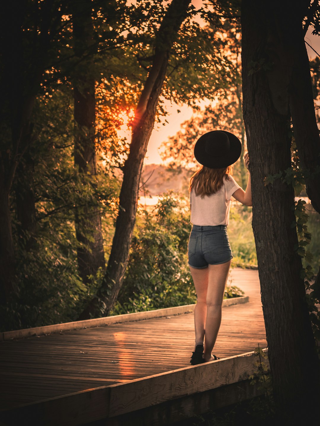 woman in white shirt and black shorts walking on wooden bridge