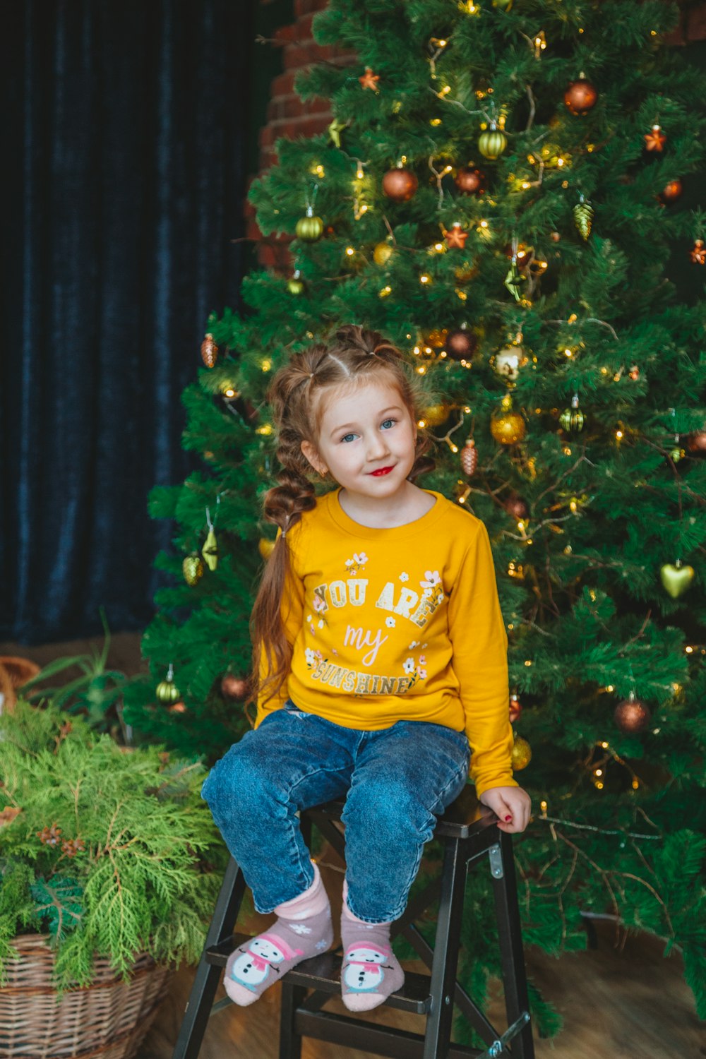 girl in yellow long sleeve shirt and blue denim jeans sitting on green grass field