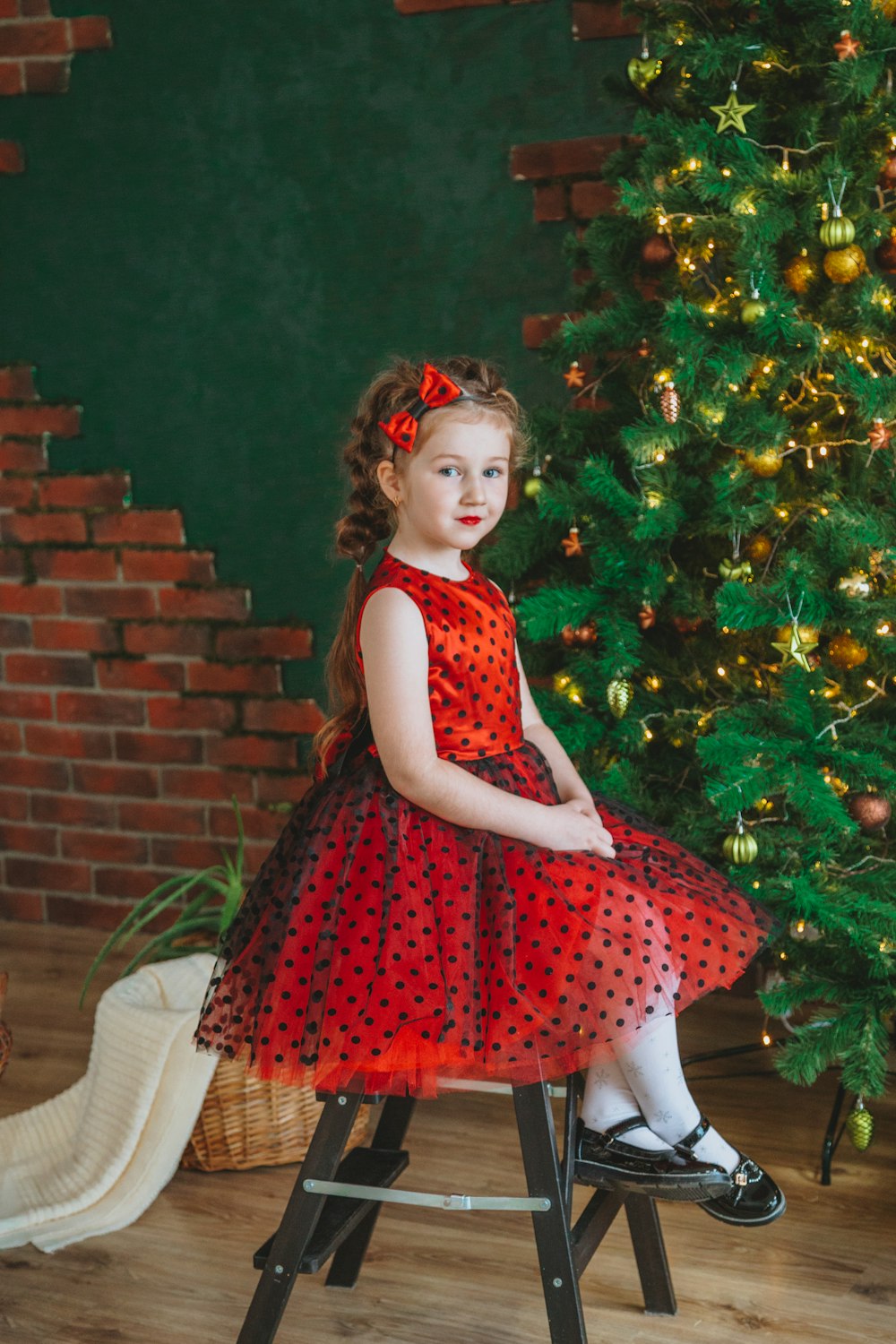 girl in red and white sleeveless dress standing beside green plant