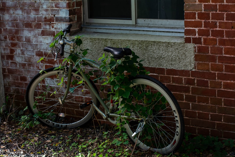 black bicycle parked beside brown brick wall