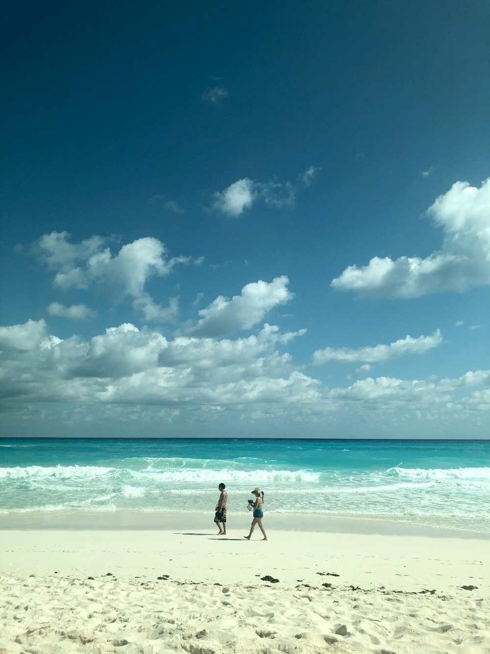 2 persone che camminano sulla spiaggia durante il giorno